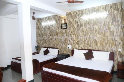 a bedroom with two beds and a wall at Arudhra Residency in Chidambaram