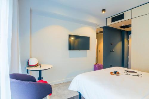 a bedroom with a white bed and a blue chair at ibis Timisoara City Center in Timişoara