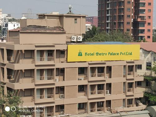 a building with a yellow sign on top of it at Hotel Metro Palace Bandra in Mumbai