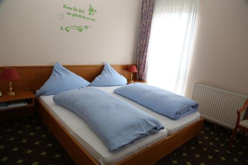 ein Schlafzimmer mit einem Bett mit blauen Kissen und einem Fenster in der Unterkunft Hotel Taunus Residence in Bad Camberg