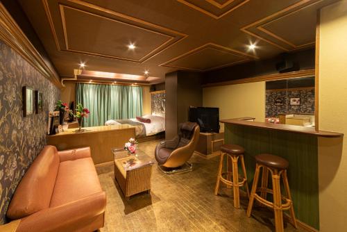 a hotel room with a couch and a kitchen and a bed at Kashiba Hotel Flower Style (Adult Only) in Kashiba
