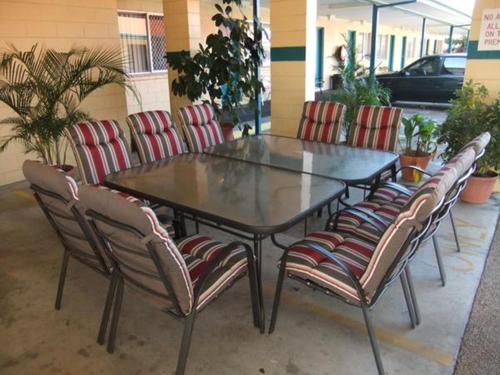 een glazen tafel en vier stoelen er omheen bij Cedar Lodge Motel in Townsville