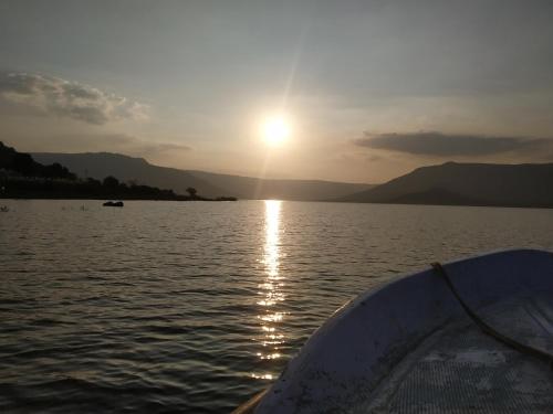 a boat in the water with the sun setting at Rutugandh Homestay Wai, Near Panchgani in Wai