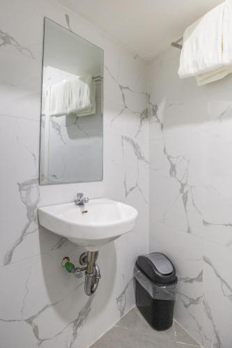 a white bathroom with a sink and a mirror at Circuit Hostel in Manila