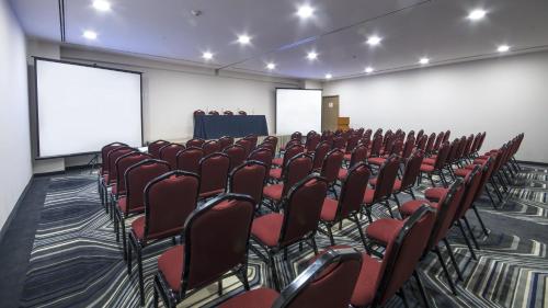 a conference room with red chairs and a screen at Holiday Inn Express Mexico- Toreo by IHG in Mexico City