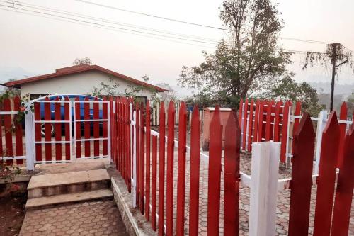 a red fence in front of a house at Joy Cottages - Premium Chalets, Vacation Home Rentals in Karjat