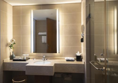 a bathroom with a sink and a mirror and a shower at Wyndham Garden Lingshui in Lingshui