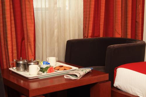a tray of food on a table next to a bed at Parijatha Gateway in Bengaluru