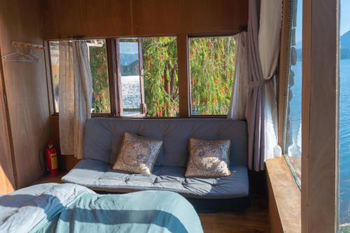 a blue couch in a room with two windows at The Lake House Dalat in Da Lat