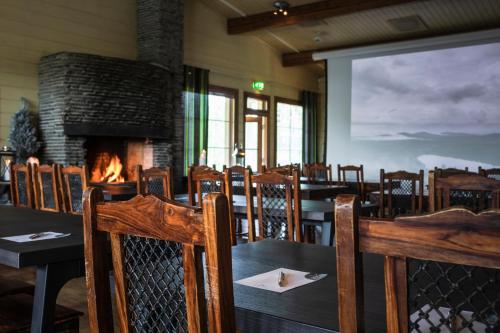 a dining room with a fireplace and tables and chairs at Lapland Hotels Ounasvaara Chalets in Rovaniemi