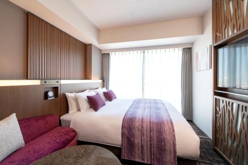 a hotel room with a large bed and a couch at Hotel GrandBach Sendai in Sendai