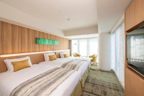a hotel room with two beds and a television at Hotel GrandBach Sendai in Sendai