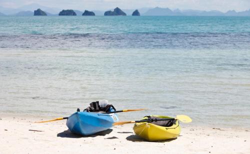 two kayaks sitting on a beach near the water at Baan Kilee in Lipa Noi