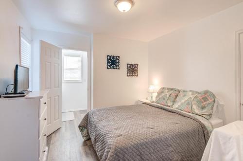 a white bedroom with a bed and a television at Margarita's in Seaside