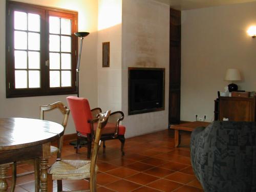 ein Wohnzimmer mit einem Tisch, Stühlen und einem TV in der Unterkunft gîte de la Herpinière in Cheillé