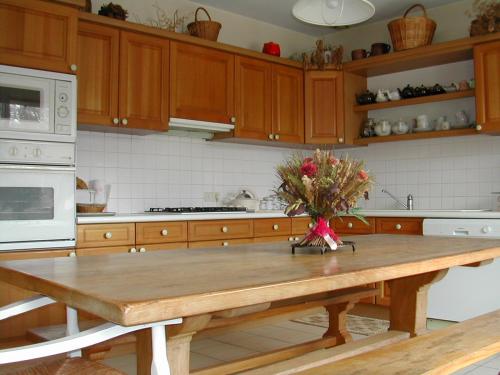 gîte de la Herpinière في Cheillé: مطبخ مع طاولة خشبية مع إناء من الزهور عليه