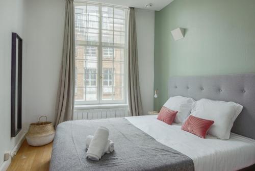 une chambre avec un grand lit avec des oreillers roses et blancs dans l'établissement NOCNOC - Le Baryton, Monnaie, à Lille