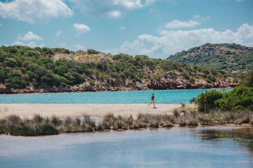 a person walking on a beach next to a body of water at Résidence Les Terrasses de Rondinara in Bonifacio