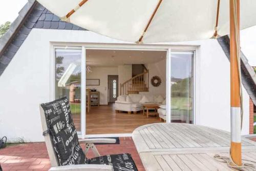 Ein weißes Haus mit einem Wohnzimmer und einer Terrasse in der Unterkunft Ferienhaus Boje 9 in Neuharlingersiel