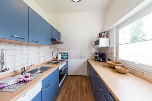 a kitchen with blue cabinets and a sink and a window at Ferienhaus Boje 9 in Neuharlingersiel