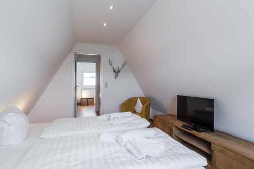 a white bedroom with a bed and a tv at Ferienhaus Boje 9 in Neuharlingersiel