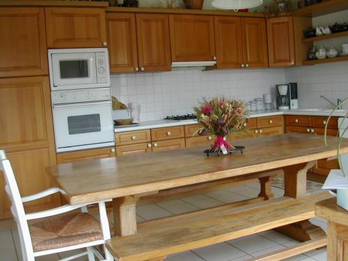 gîte de la Herpinière في Cheillé: مطبخ مع طاولة خشبية مع إناء من الزهور عليه