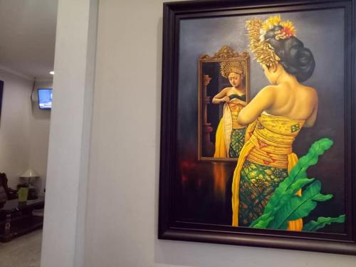 a painting of a woman in a mirror on a wall at Helena Guest House in Rampal
