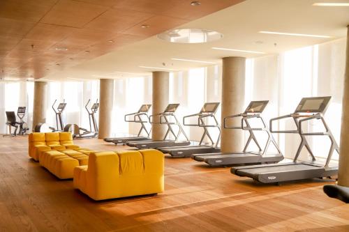 a gym with a row of treadmills and yellow chairs at Maritim Hotel Plaza Tirana in Tirana