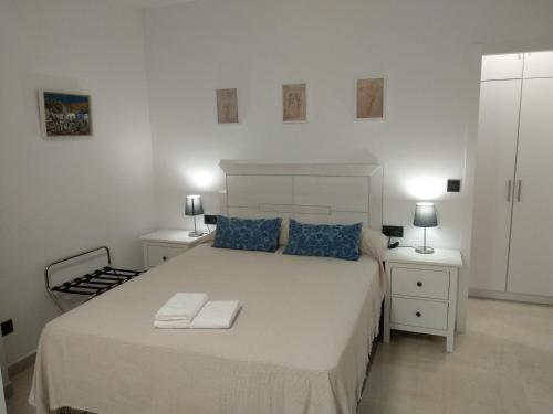 a white bedroom with a large bed with two night stands at Apartamentos Cordoba in Córdoba