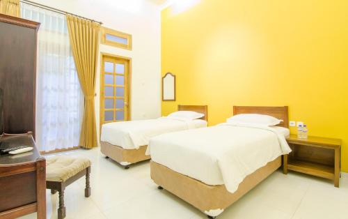 a room with two beds and a table and a desk at Helena Guest House in Rampal