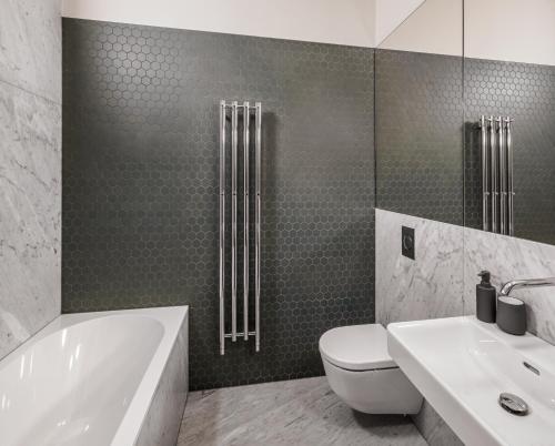 a bathroom with a tub and a toilet and a sink at MN6 Luxury Suites by Adrez in Prague