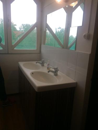 a bathroom with a sink and two windows at Y HOSTEL in Balatonlelle