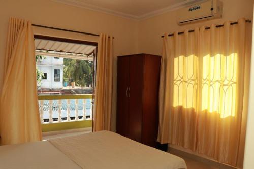 a bedroom with a bed and a window with a balcony at Peter’s vacation rentals Goa in Calangute