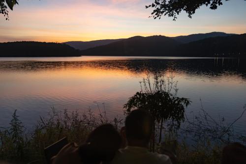 a group of people sitting next to a lake at sunset at The Lake House Dalat in Da Lat