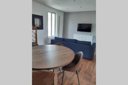 un salon avec une table et un canapé bleu dans l'établissement la causerie, à Courseulles-sur-Mer