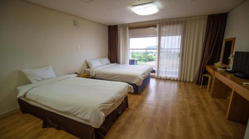 a hotel room with two beds and a television at Hi Jeju Hotel in Jeju