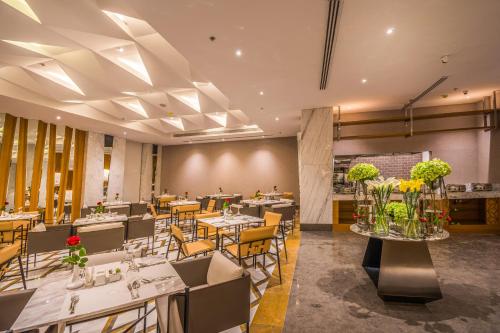 uma sala de jantar com mesas, cadeiras e flores em Grand Plaza Hotel - KAFD Riyadh em Riade