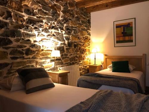 a bedroom with two beds and a stone wall at Vitori's House Tourist Accommodation in Ahedo