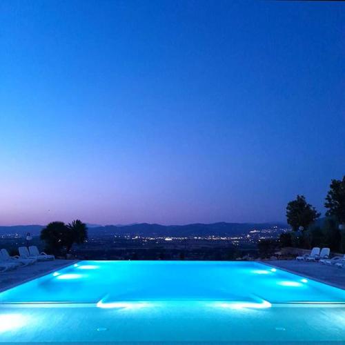 a swimming pool lit up at night at Il Poggio degli Olivi in Bettona
