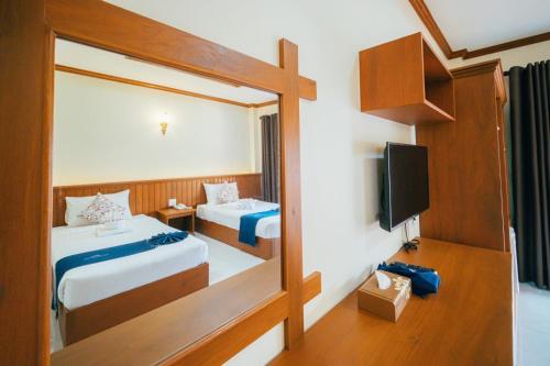 a hotel room with two beds and a mirror at Huen Him Kong Hotel Phrae in Phrae