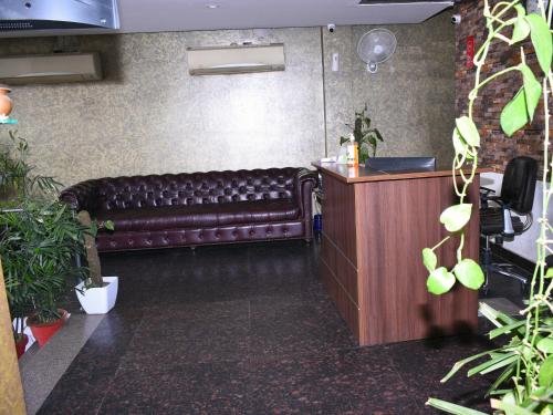 un banc en cuir brun dans une pièce ornée de plantes dans l'établissement Hotel Flora Inn, à Gurgaon
