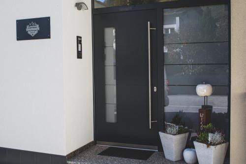 a black front door of a building with potted plants at Alpenapart Hochzeiger in Jerzens