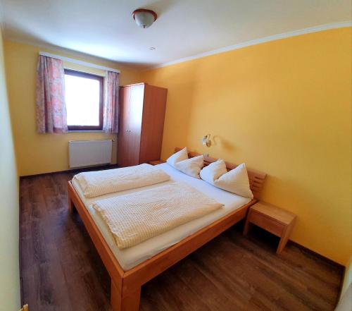 a bedroom with a bed with yellow walls and a window at Appartement zur Post in Ferlach