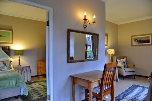a bedroom with a table and a mirror and a bed at Owls Loft Guest House in Midrand