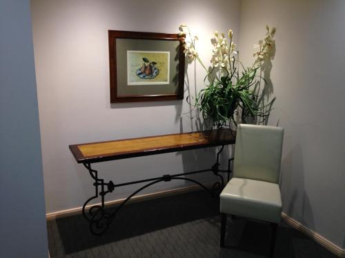 a table and a chair and a plant on a wall at Cairns Sheridan Hotel in Cairns