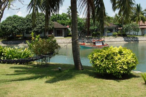 a boat in the water next to a palm tree at Rock Garden E28 Pool villa in Mae Pim