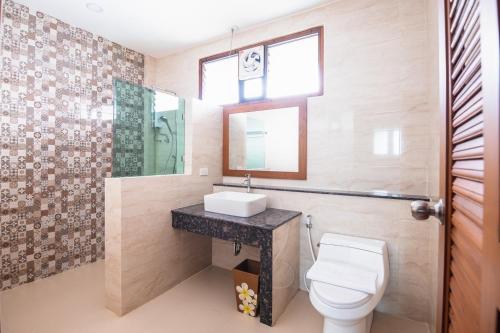 a bathroom with a toilet and a sink and a mirror at Huen Him Kong Hotel Phrae in Phrae