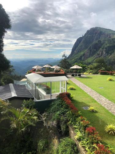 a house on top of a green field with mountains at EKHO Ella - A Divine View of Ella Gap in Ella