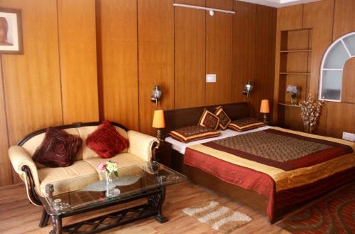 a bedroom with a bed and a couch and a table at Hotel Himshikhar in Chaukori