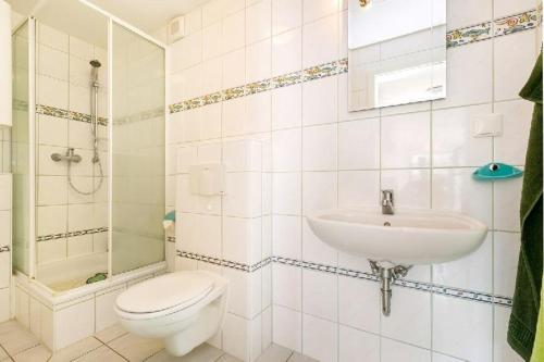 een witte badkamer met een toilet en een wastafel bij RügenHerz Strandliebe in Parchtitz